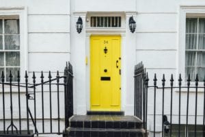 Adding curb appeal to a white home is easy with a contrasting yellow door.