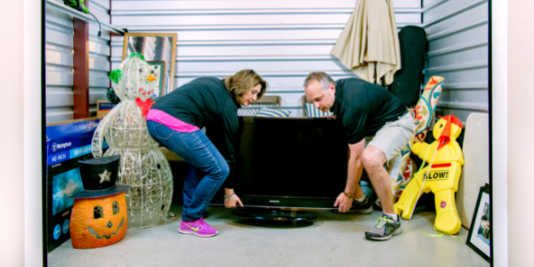 couple moving tv and other belongings into a storage unit